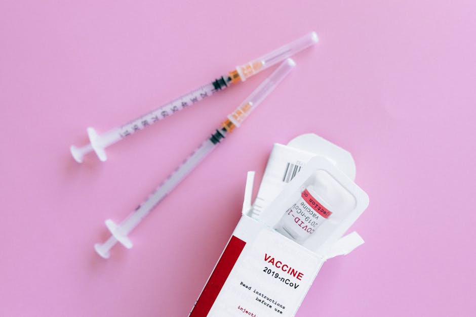 Close-up of vaccine vial and syringes on a pink background, representing healthcare.